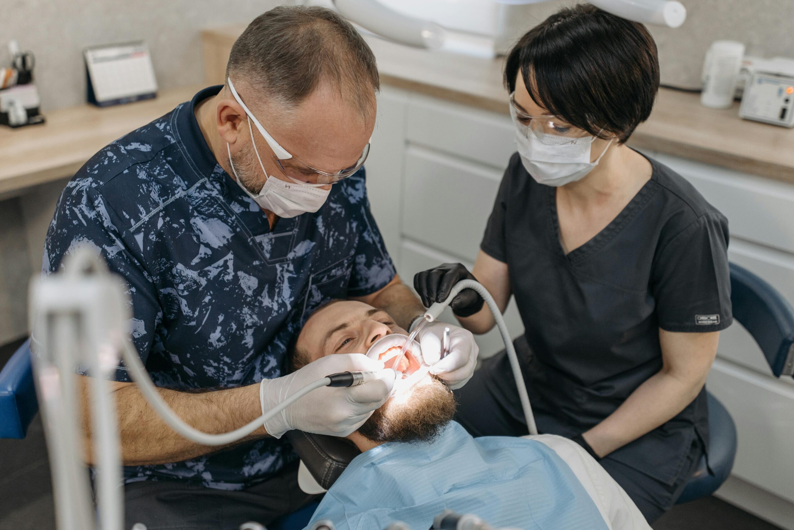 Dentist and assistant conducting a dental exam with protective gear.